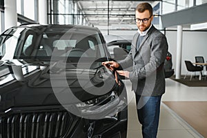 Man adult customer male buyer client wears classic suit white shirt chooses auto wants to buy new automobile touch check