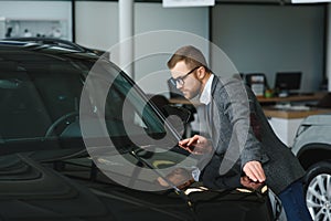 Man adult customer male buyer client wears classic suit white shirt chooses auto wants to buy new automobile touch check