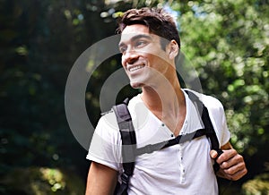 Man, adventure and backpack for hiking in rainforest with smile for thinking, holiday and outdoor in summer. Person