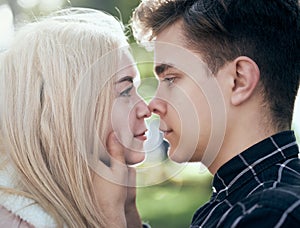 A man affectionately call looks at woman, guy and girl are worth close, touching the tips noses. Concept of teenage love and first