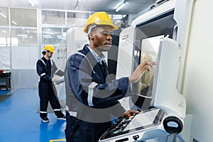 Man African American engineer using computer controlling cnc machine at workshop. professional male control automated machine