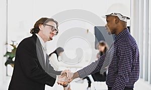 A man African American and Leadership caucasian architects shake hand for success in meetings and presentations on design in