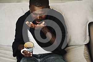 man african appearance at home drinking pills cold