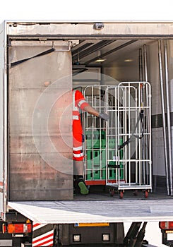 Man of African ethnicity in reflective workwear loading dairy products in refrigerated van