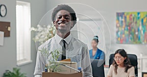 Man with afro hair quits company job walks out of office with things packed in box leaves corporation quits