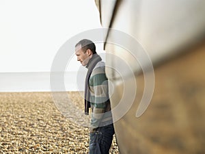 Man Against Wooden Hull Of Boat At Beach