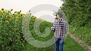 Man agronomist farmer with a digital tablet computer standing in sunflower field using apps, internet for smart farming