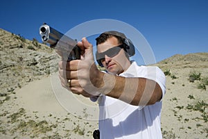 Man Aiming Hand Gun At Firing Range In Desert