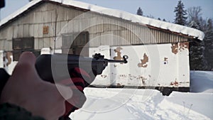 A man aiming a pellet gun towards a target, practicing his aim in the winter. Clip. The shooter in camouflage targets a