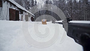 A man aiming a pellet gun towards a target, practicing his aim in the winter. Clip. The shooter in camouflage targets a