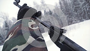 A man aiming a pellet gun towards a target, practicing his aim in the winter. Clip. The shooter in camouflage targets a