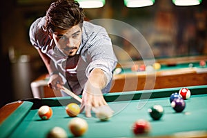 Man aiming at pool ball to billiard game