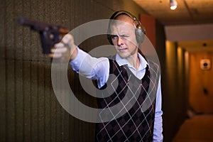 Man aiming smallbore sporting pistol at target in shooting range