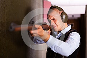 Man aims at a target with a semi-automatic rifle in shooting range