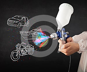 Man with airbrush spray paint with car, boat and motorcycle draw