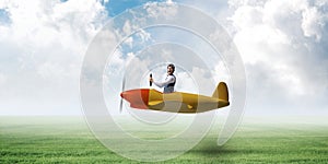 Man in airplane flying low above green meadow