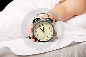 Man with alarm clock in bedroom.