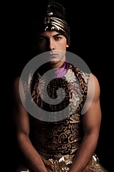 Man in alladin costume posing in dark studio background hands do