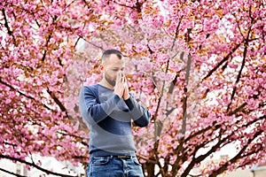 Man allergic suffering from seasonal allergy at spring, sneezing and blowing nose with handkerchief.