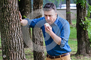 Man with allergy or ill with hay fever sneezing and cleaning nos photo