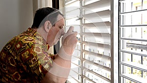 Man in aloha shirt shooting through plastic jalousies