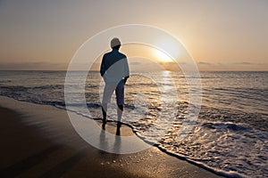 Man alone on beach watching the sunset