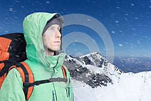 Man alpinist looks up against a winter mountain landscape.