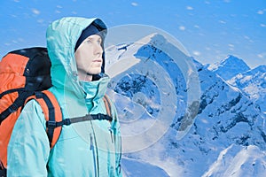 Man alpinist looks up against a winter mountain landscape.