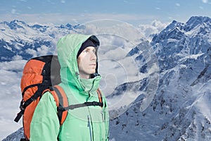 Man alpinist looks up against a winter mountain landscape.