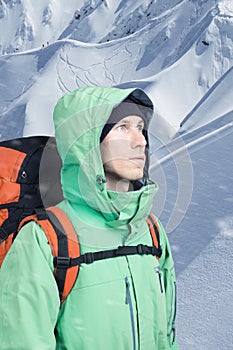 Man alpinist looks up against a winter mountain landscape.