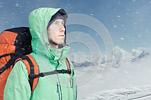 Man alpinist looks up against a winter mountain landscape.