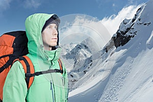 Man alpinist looks up against a winter mountain landscape.