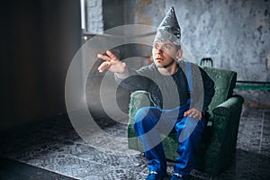 Man in aluminum foil helmet reaches out to the TV