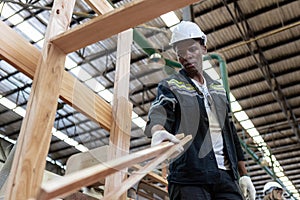 man American African wear uniform and white hard hat working checking quality inspection length size of wooden products at
