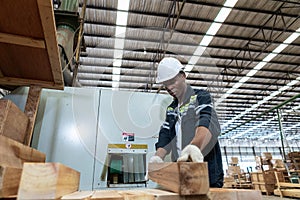 Man American African wearing safety uniform and hard hat working on wood sanding electric machines at workshop manufacturing