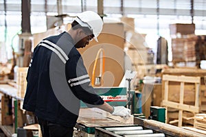 Man American African wearing safety uniform and hard hat working on wood sanding electric machines at workshop manufacturing