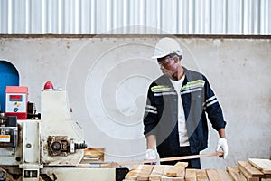 Man American African wearing safety uniform and hard hat working on wood sanding electric machines at workshop manufacturing