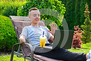 Man with amputated arm drinks a cocktail and talking with friends via laptop