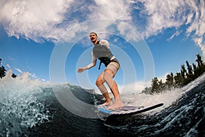 man with an amputated hand wakesurfing on the board down the wave against the background of sky