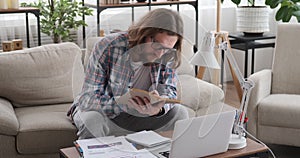 Man analysing documents and reading book at home office