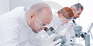 Man analyzing under microscope photo