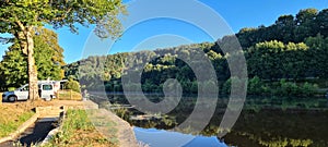 Man angling beside river on a sunny morning