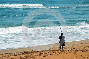 Man angling in surf from beach photo