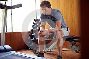 Man Anxious About Body Image Sitting On Weight Bench In Home Gym