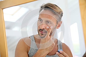 Man applaying anti-aging cream on his face