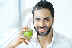 Man With Apple. Beautiful male With White Smile, Healthy Teeth.