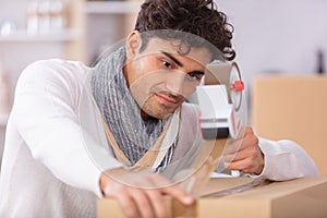 man applying adhesive tape on packing box