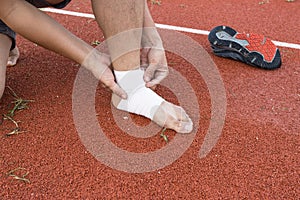 Man applying compression bandage onto ankle injury of a football player, Sports injuries