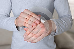 Man applying cream on his hands indoors, closeup