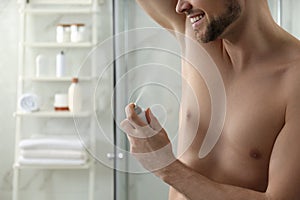 Man applying deodorant in bathroom. Space for text